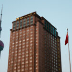 Tall building with a red flag on top and clear blue sky in the background