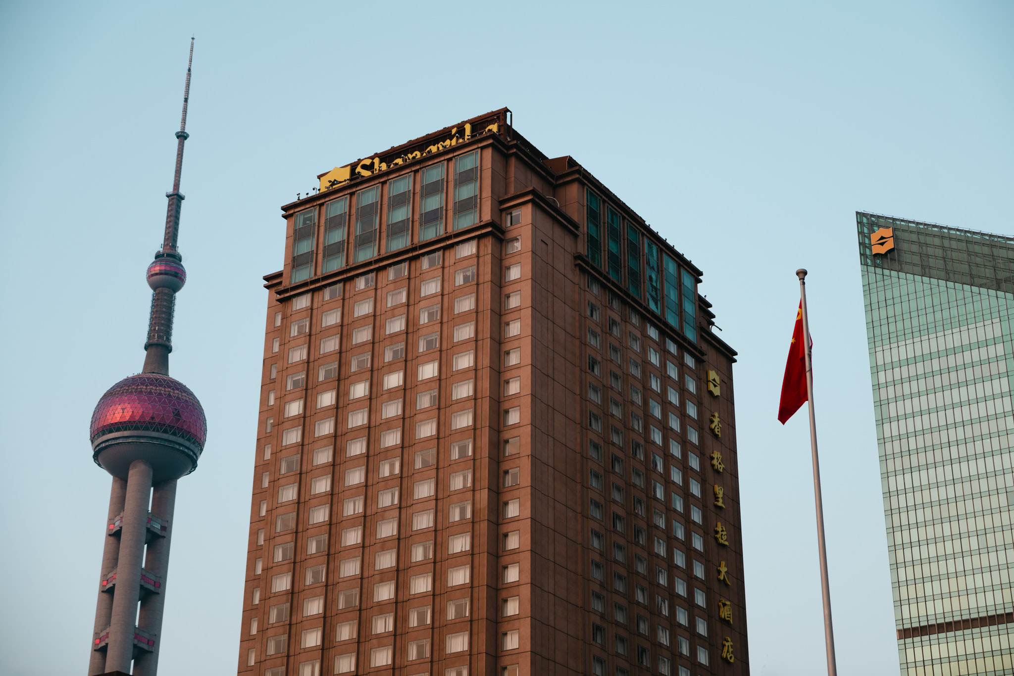 Tall building with a red flag on top and clear blue sky in the background