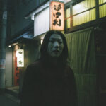 Woman standing on a dark Nagoya street at night.