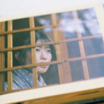 Photo of a woman behind a wooden lattice.