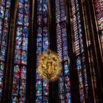 Aachen Cathedral's interior with colorful stained-glass windows and a golden Madonna and Child sculpture.