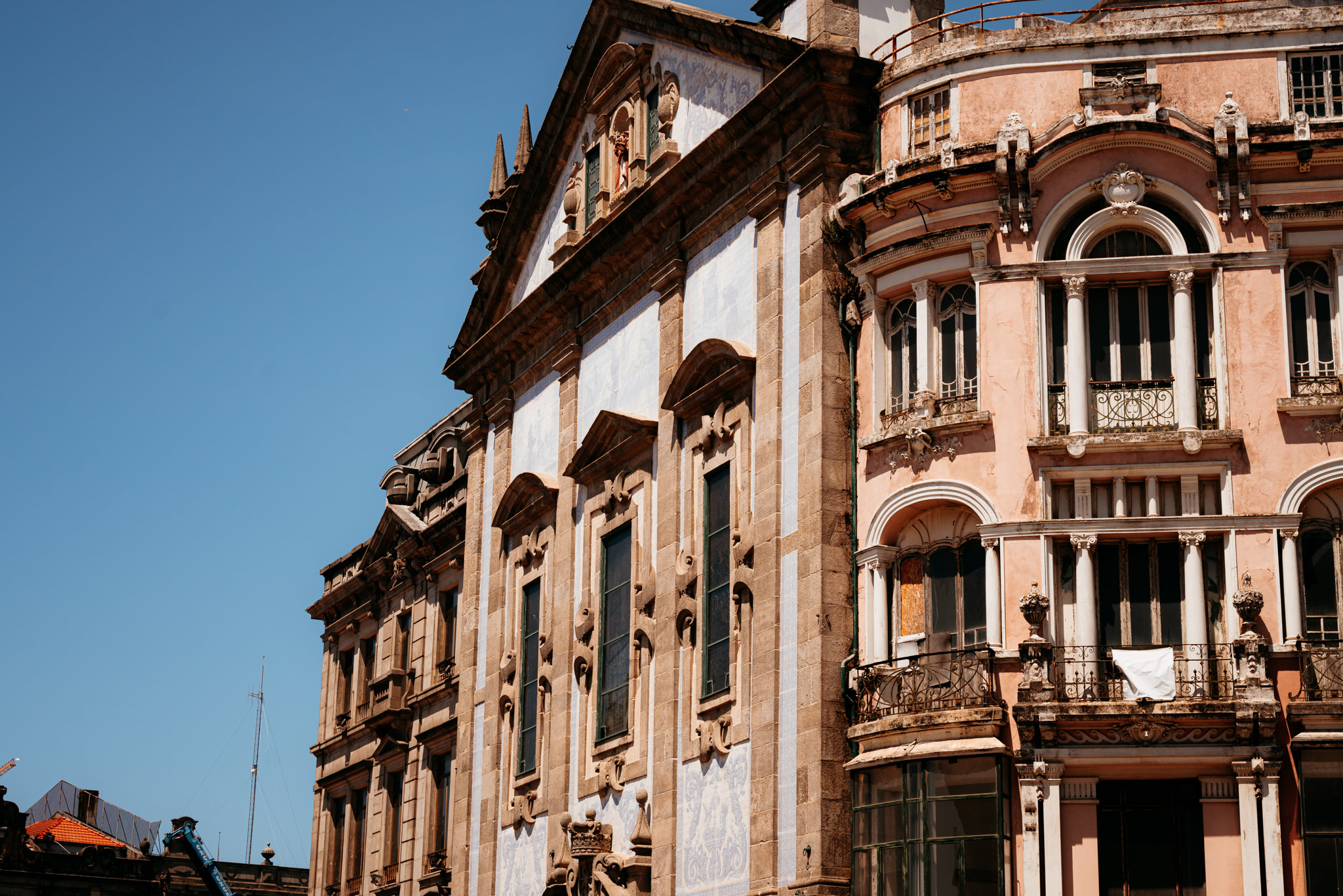 Two adjacent historic buildings in Porto, Portugal, one stone and one peach-colored, both ornate.