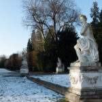 Snow-covered park with classical statues.